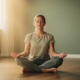Persoon zit gekruist op houten vloer in meditatieve ademhalingsoefening, ogen gesloten, zachte ochtendzon door hoog raam.