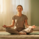 Beginner meditatief zittend in kleermakerszit op yogamat, ogen gesloten, handen op knieën in zacht ochtendlicht.